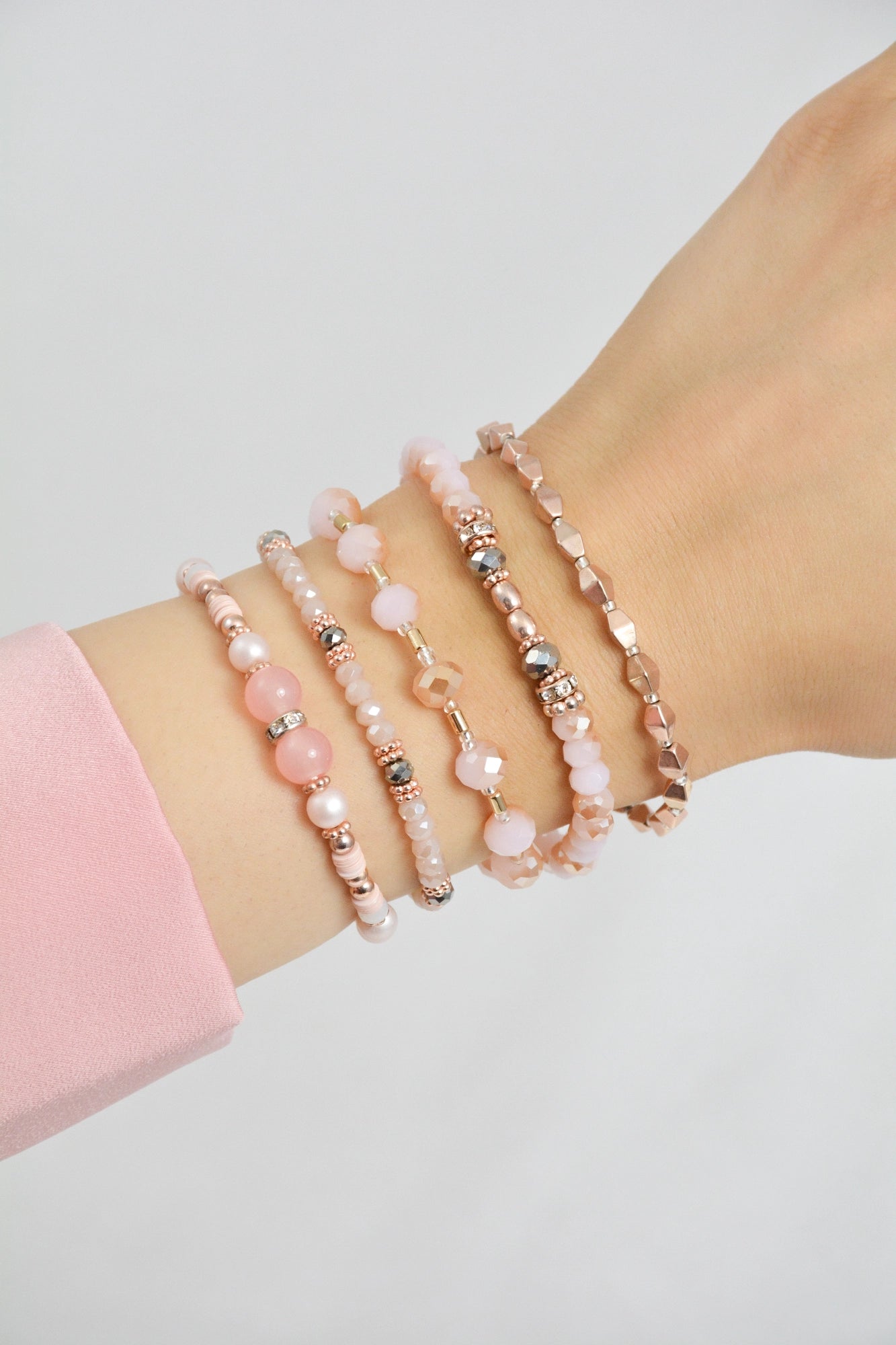 5‑teiliges Armband Set Mariposa getragen am Handgelenk – rosa, weiß und roségoldfarbenes Modeschmuck‑Set