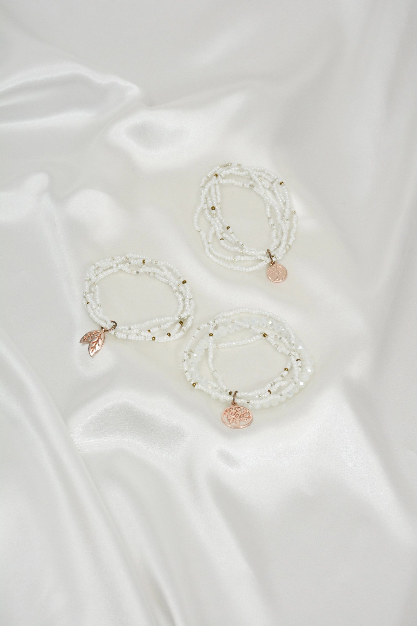 White Fantasy Armband Set liegend – einzelne weiße und rosegoldfarbene Modeschmuck Armbänder