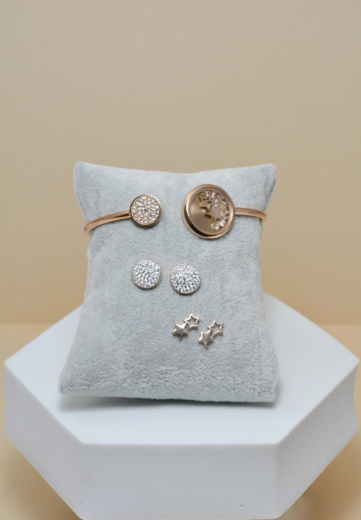 Sparky Edelstahl Schmuckset roségoldfarben – offener Armreif und zwei Ohrstecker auf Präsentationskissen, minimalistischer Modeschmuck