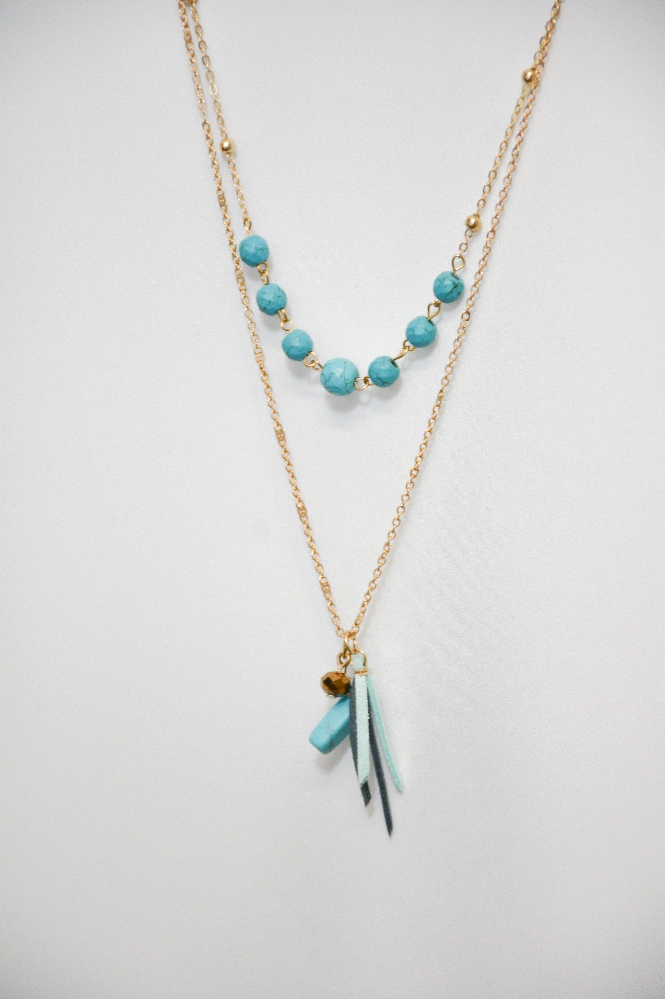 Detailaufnahme der Kette Turquoise mit türkisfarbenen Perlen und goldfarbenem Metall‑Design